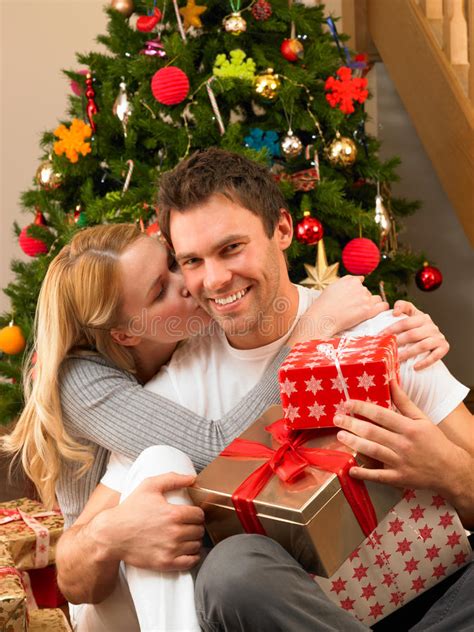 People of all ages celebrate this festival with cheer and fervour. Young Couple With Gifts In Front Of Christmas Tree Stock ...