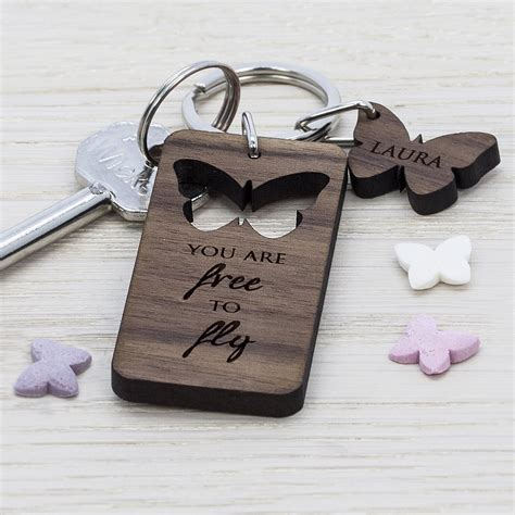 A Wooden Keychain With Two Butterflies And The Words You Are Free To