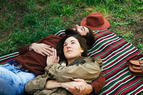 Overhead Of Couple Embracing Together Resting On A Striped Blanket In The Park By Stocksy