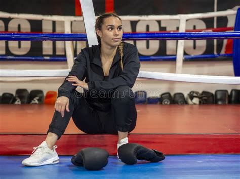Boxer Girl Sitting In Front Of Boxing Ring With Black Boxing Gloves