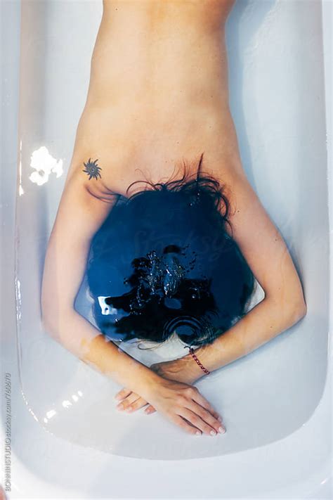 Child bathing outdoors in spring. Back view of a woman relaxing underwater in the bathtub ...