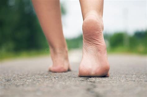 Young Girl Walking Barefoot Along Asphalt Road Close Up Rear View Stock