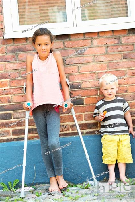 Girl With Crutches And Boy Looking At Camera Stock Photo Picture And