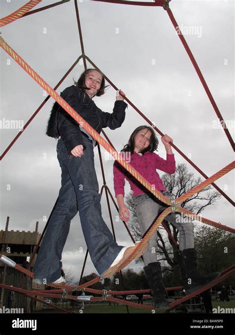 Two Girls Playing On Rope Climbing Frame Stock Photo Alamy