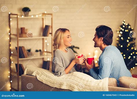 Couple Celebrating Christmas At Home Relaxing With Cups Of Coffee