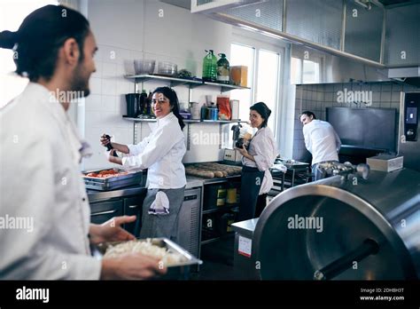 Happy Chefs Looking At Colleague In Commercial Kitchen Stock Photo Alamy
