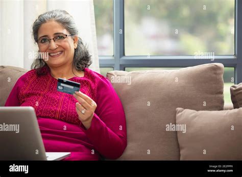 A Senior Adult Woman Holding Debit Card And Laptop To Do Online