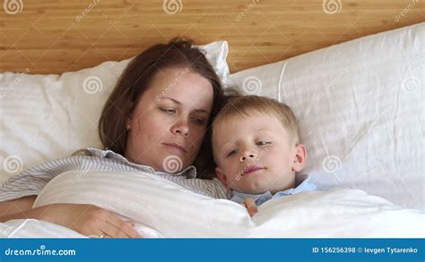 Close Up Of Sleepy Mom And Son Lying On White Pillows On The Bed In The Bedroom Stock Footage