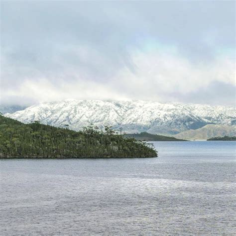 A Large Body Of Water Surrounded By Snow Covered Mountains In The