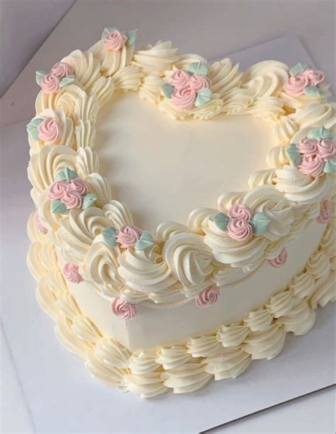 A Heart Shaped Cake With White Frosting And Pink Flowers On It S Edges