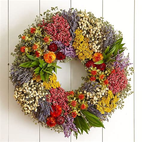 A Wreath Made Out Of Dried Flowers On A White Wall