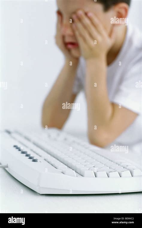 Boy Holding Head Computer Keyboard In Foreground Stock Photo Alamy