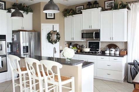 The top recommended among kitchen soffit ideas is to install false cabinet doors above the normal kitchen cabinets. Greenery above kitchen cabinets ideas in white painted ...