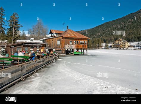 Dobbiaco Lake In Winter With Bar Restaurant On Stilts And Historic