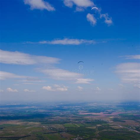 Paragliders Fly Over The Green Plain Under The Blue Sky Stock Image