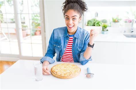Young African American Woman Eating Homemade Cheese Pizza Screaming Proud And Celebrating