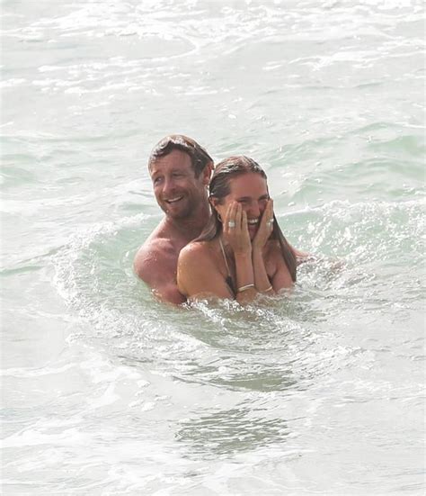 A Man And Woman Are In The Water With Their Hands On Each Other S Faces