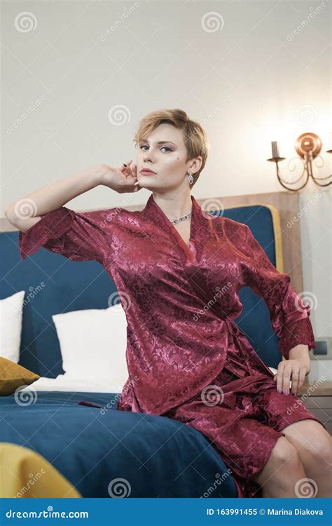 stylish pin up short hair blonde woman with plus size curvy body posing in fashion red bathrobe