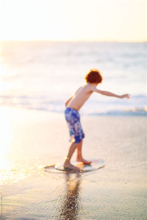 Child Riding A Skim Board At The Beach At Sunset Del Colaborador De