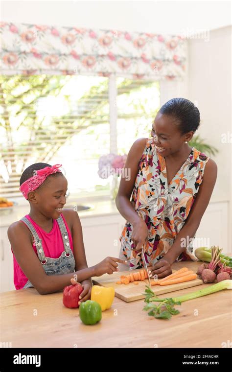 Smiling African American Mother Teaching Daughter Cooking In The