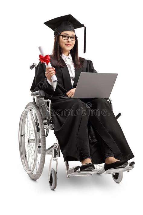 jonge vrouw in een rolstoel die een graduatietoga dragen en een diploma en laptop houden stock