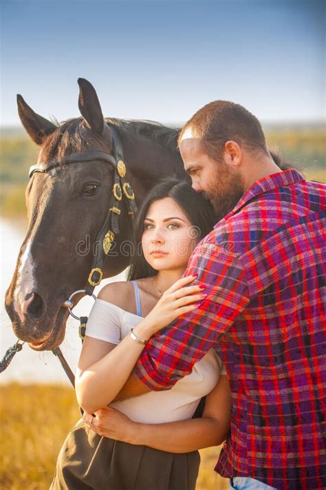 Brunette Girl And Brutal Guy With A Beard With A Black Horse Stock