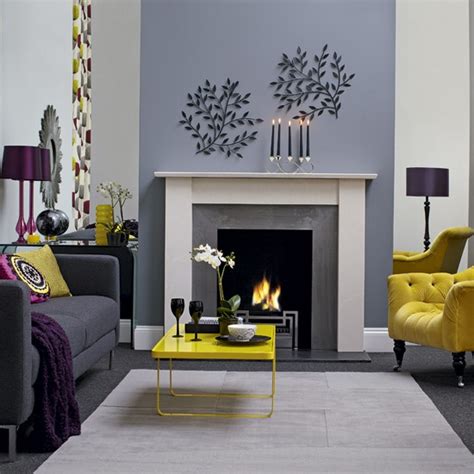 This living room is designed with a photo gallery mounted above the blue velvet sofa that's lighted by a cascading chandelier. Modern Grey And Yellow Living Room Designs