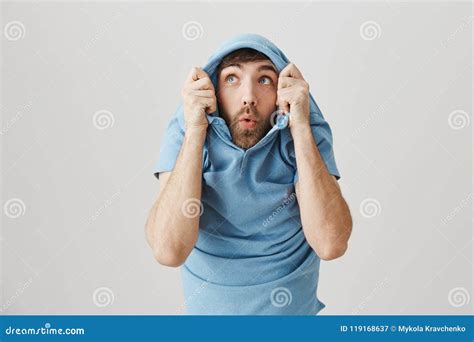 Positive Funny European Male Pulling Shirt On Head And Staring Through