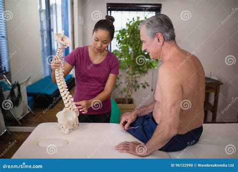 Female Therapist Explaining Shirtless Senior Male Patient With Artificial Spine Stock