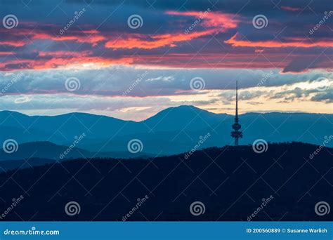 Canberra`s Telstra Tower At Sunset With Layers Of Clouds And Mountains