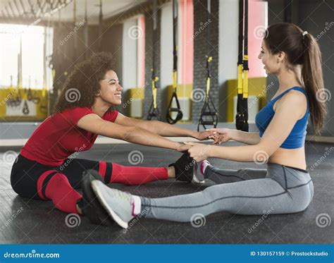 Women Sitting With Spread Legs Stretching Each Other Stock Image