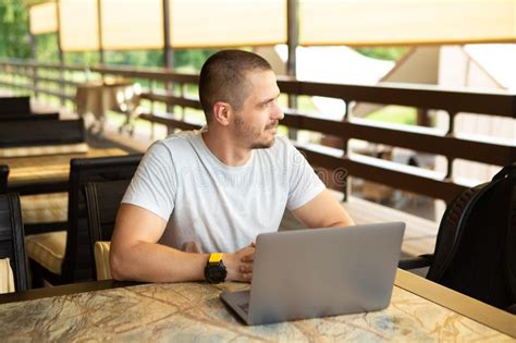 Man Freelancer Looking Away Sitting On Desk In Cafe With Laptop Stock