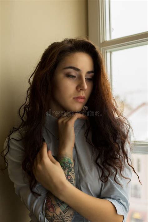 Amazing Brunette Woman With Curly Hair And A Tattoo On Her Arm Stock