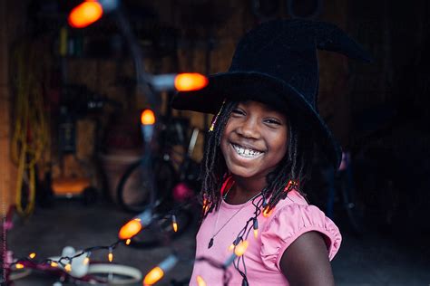 smiling african american girl with witch hat and orange hallowee by stocksy contributor gabi