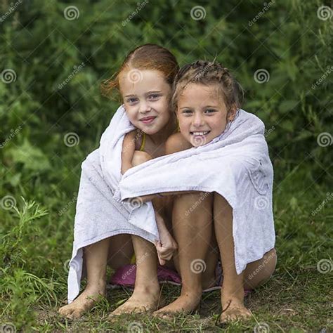 Two Naughty Little Girls Sitting On The Beach In A Towel After A Bathe