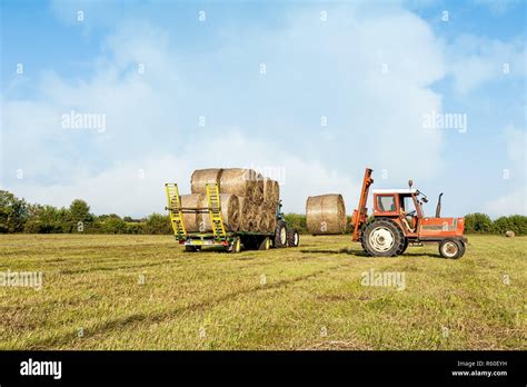 Agricultural Scene Tractor Lifting Hay Bale On Barrow Stock Photo Alamy