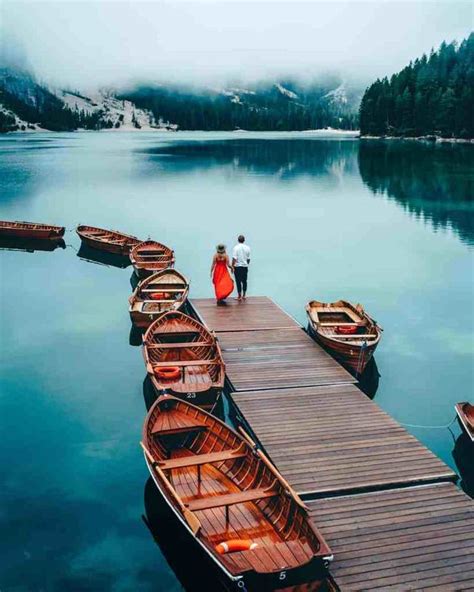 Two People Standing On A Dock Next To Several Small Wooden Boats In The