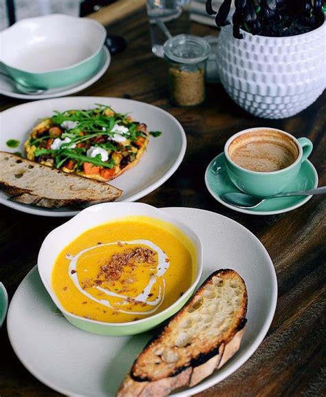 A Wooden Table Topped With Plates Of Food And Bowls Of Soup Next To Toasted Bread