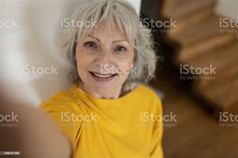 An Older Grayhaired Lady In A Yellow Sweater Takes A Selfie A Look