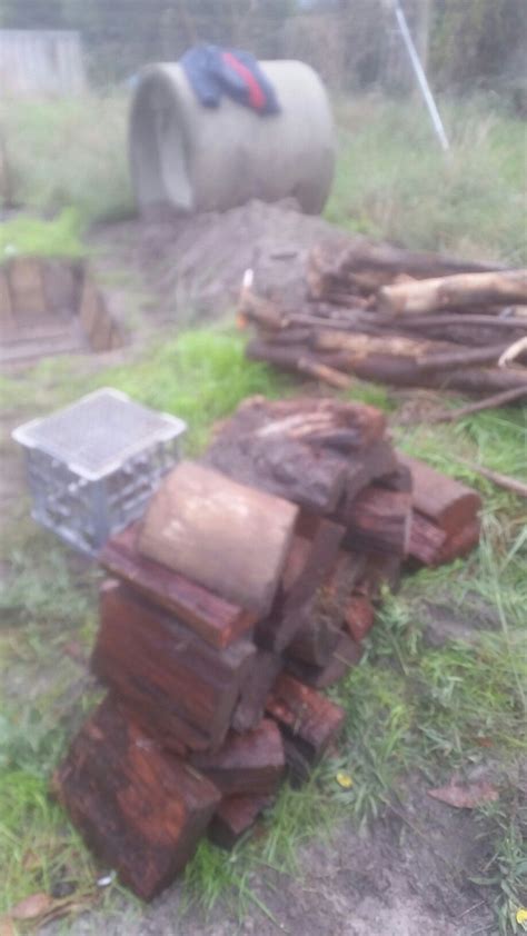 A Pile Of Wood Sitting On Top Of A Grass Covered Field Next To A Metal