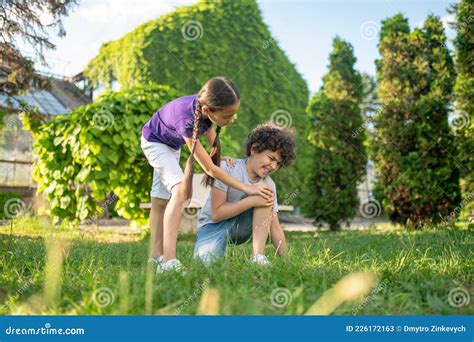 Girl Bending Over To Boy Sitting On Grass Stock Image Image Of Injury