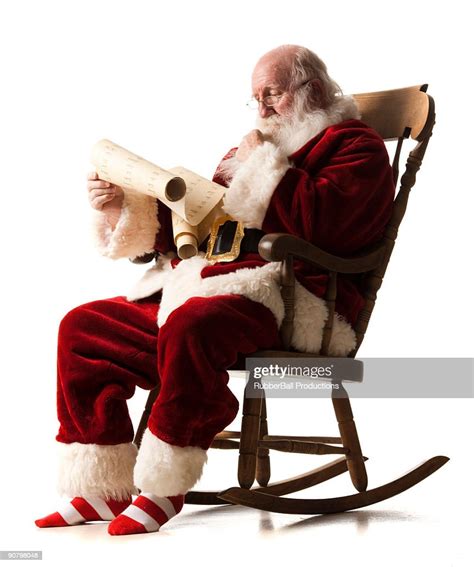 Santa Claus Sitting In A Rocking Chair Going Over His List High Res