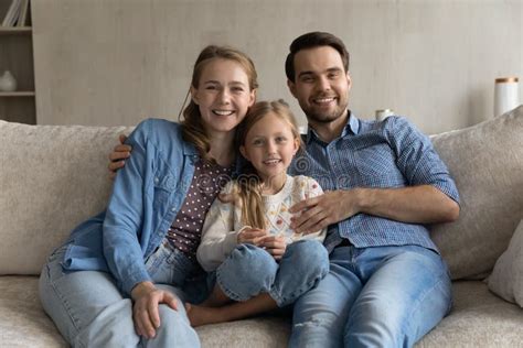 Smiling Young Parents And Little Daughter Sitting On Sofa Stock Image