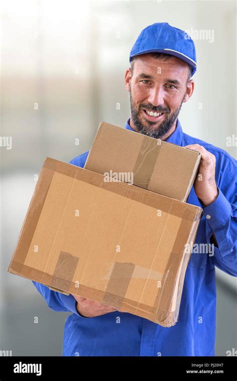 delivery guy holding big parcel and smiling isolated on white stock