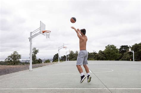 Male Teenage Basketball Player Jumping And Throwing Ball Toward