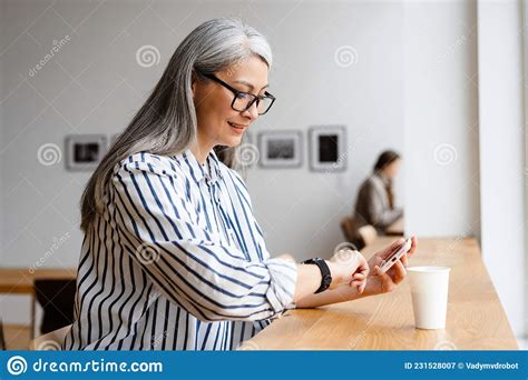 Smiling White Haired Mature Woman Drinking Coffee And Using Cellphone Stock Image Image Of