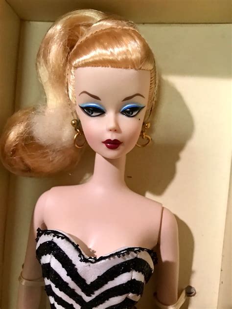 A Close Up Of A Barbie Doll With Blonde Hair And Blue Eyes Wearing A Black And White Dress
