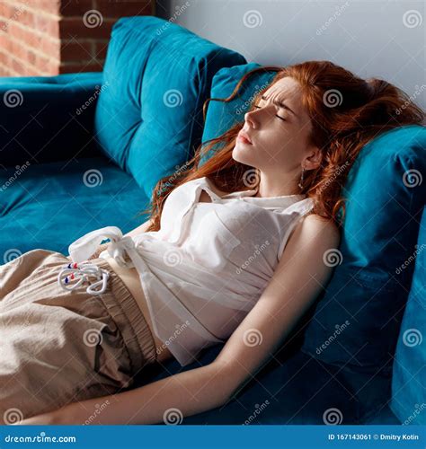 Young Redhead Woman Reclining On The Couch And Feels Tired Stock Image