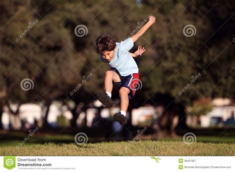 Muchacho Joven Feliz Que Salta Y Que Juega En El Parque Imagen De