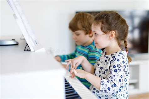 Two Little Kids Girl And Boy Playing Piano In Living Room Or Music